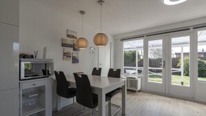 A modern kitchen with a dining table, chairs, and pendant lights. - Modern Holiday Home With Large Garden (Sint Maartensvlotbrug)