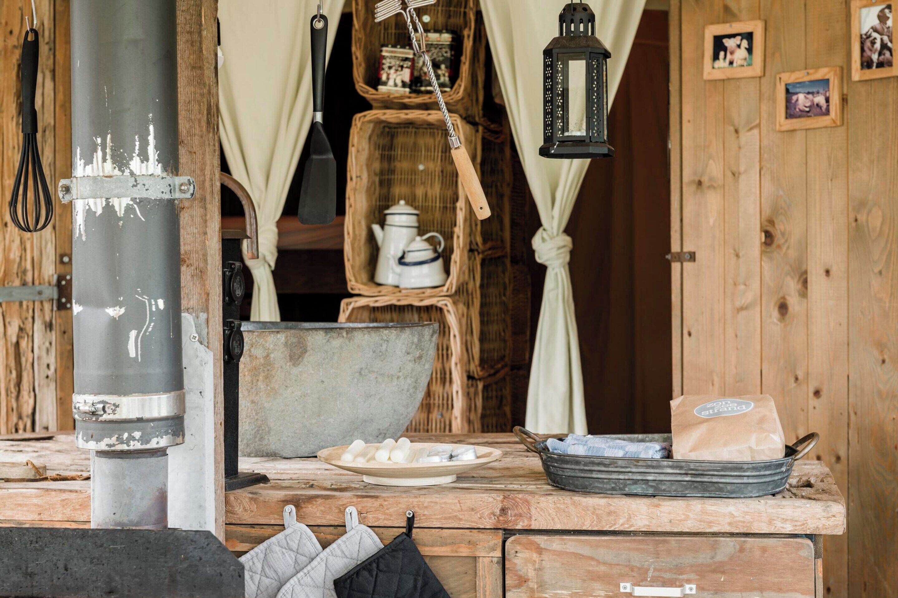 Una cucina rustica con un camino a legna, un bollitore, una pentola grande e un cesto con una teiera.