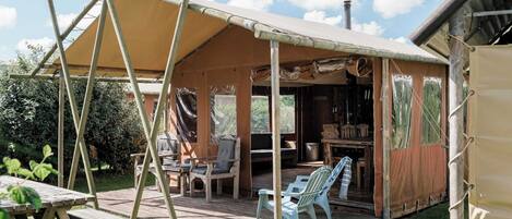 A rustic wooden structure with a covered patio, outdoor seating, and a view of the surrounding greenery.
