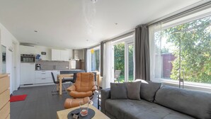 A modern living room with a grey sofa, a wooden coffee table, and a dining area with a chair and table.