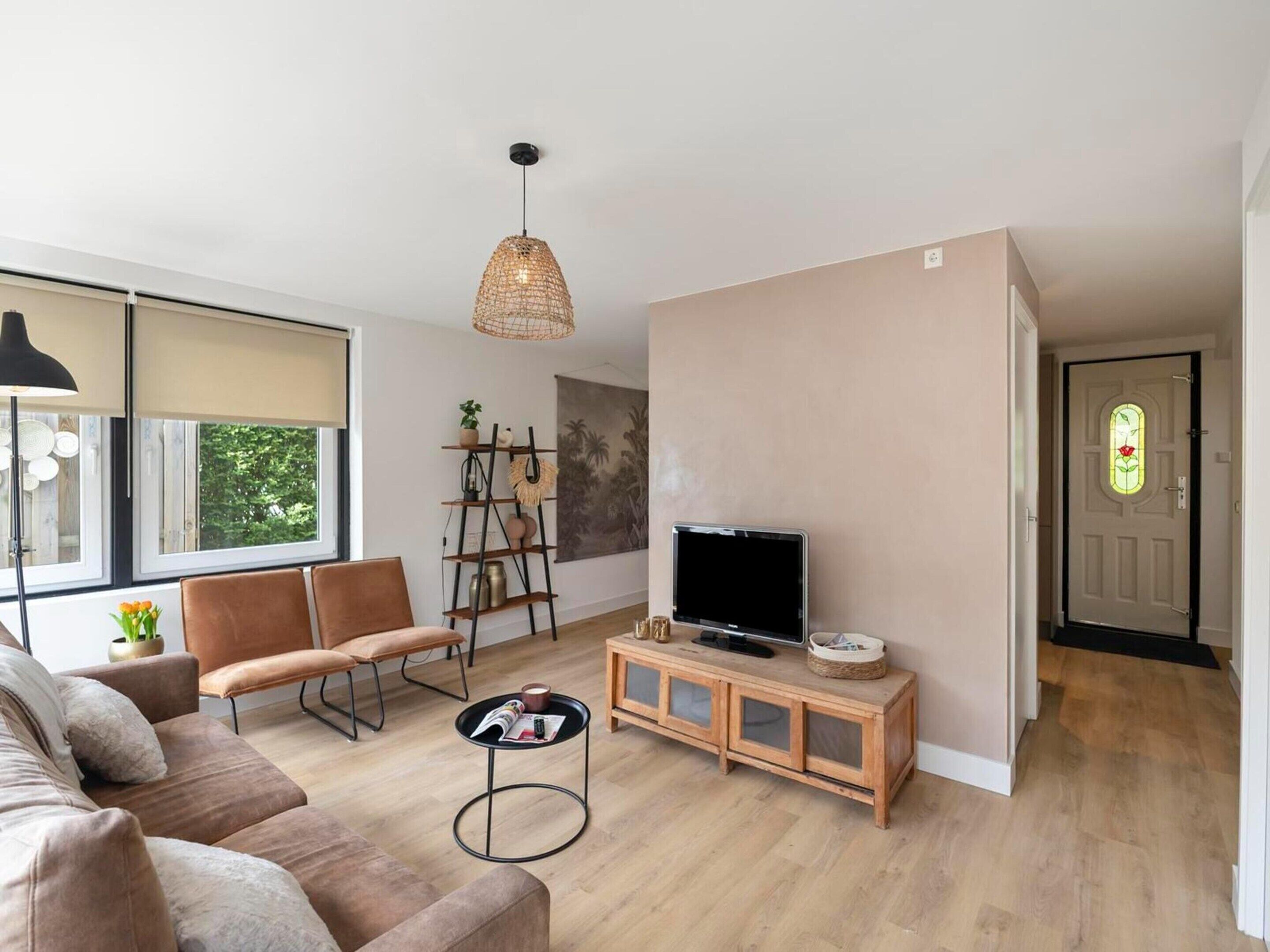 A modern living room with a sofa, a coffee table, a TV, and a bookshelf.