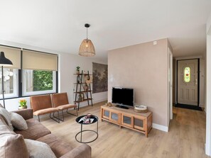 Un salon moderne avec un canapé, une table basse, un téléviseur et une bibliothèque.