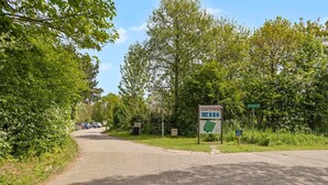 Une route asphaltée mène à un espace de stationnement où un panneau indique l’entrée du parc.