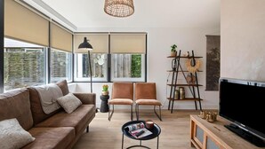 Un salon moderne comprenant un canapé, des fauteuils, une table basse, un téléviseur et une bibliothèque.