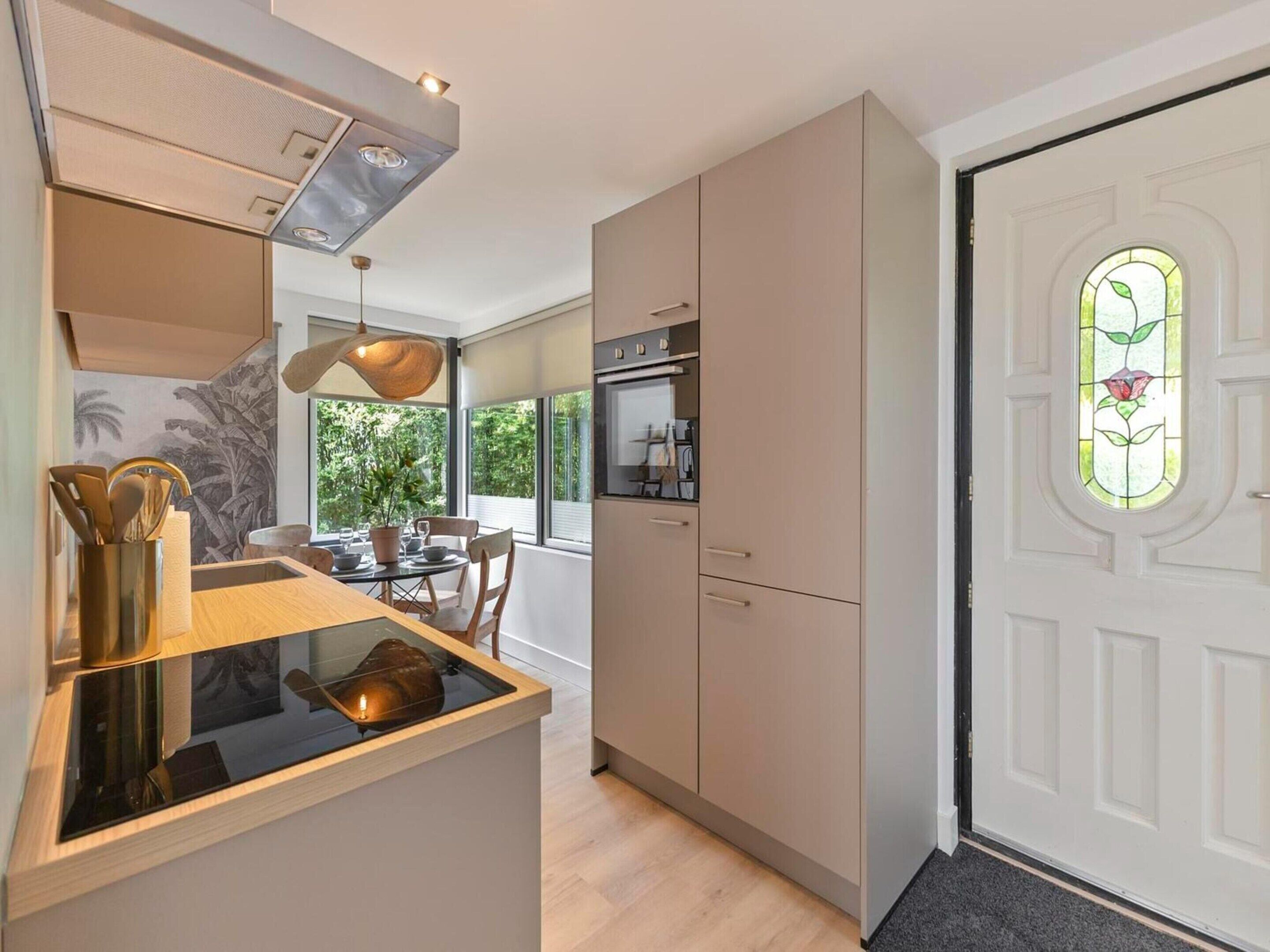 Una cucina moderna con zona pranzo, forno integrato e un'ampia finestra.