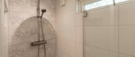 A shower with a handheld showerhead and a wall-mounted control panel.