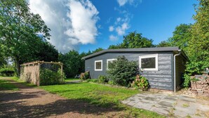 Une maison de plain-pied à l’extérieur gris, dotée d’un porche à l’avant et d’un petit jardin.