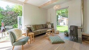 Un salon chaleureux avec un canapé, un fauteuil, une petite table et une cheminée.