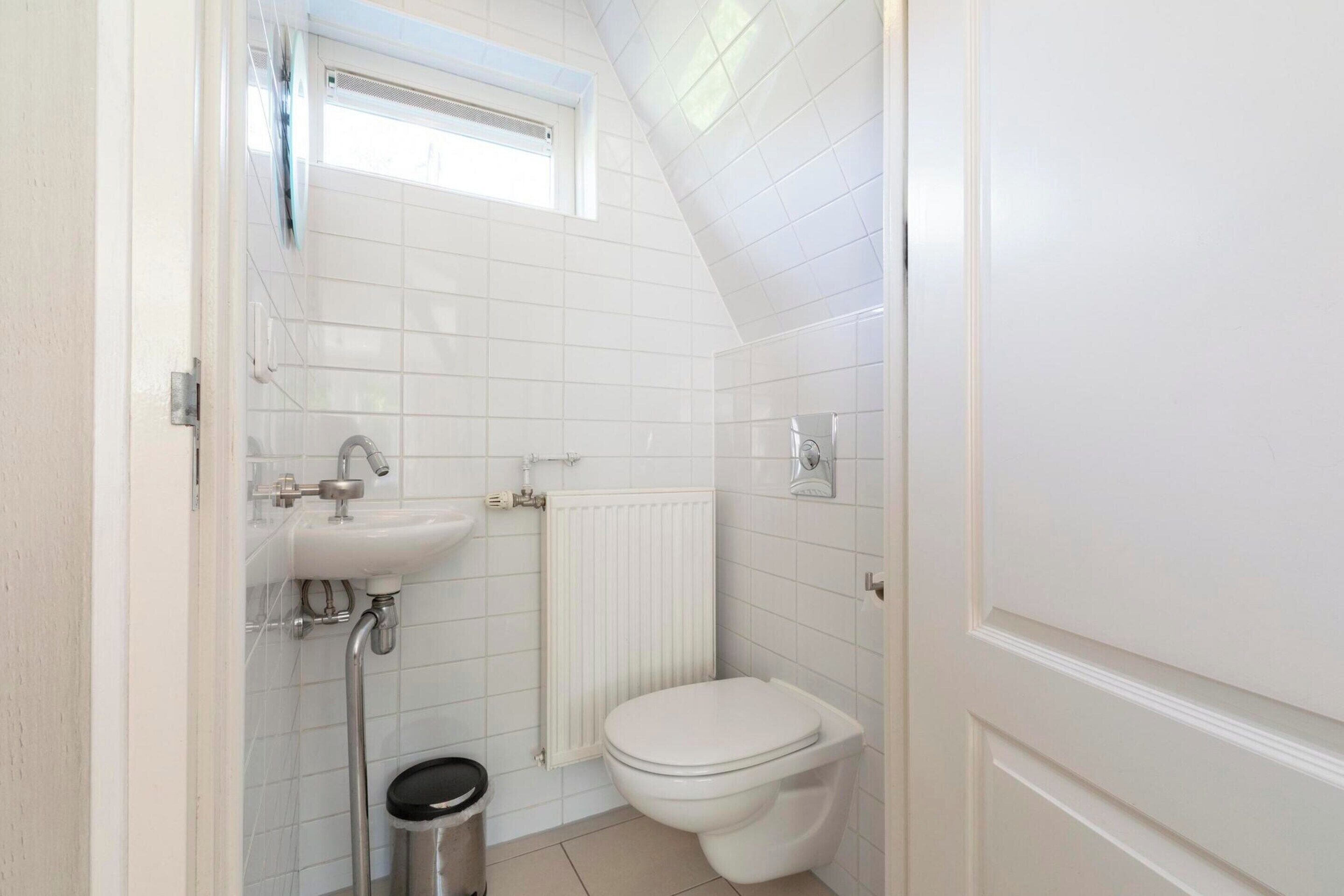 Et lille badeværelse med toilet, håndvask og brusebad.