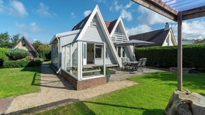 A modern house with a sloped roof, a covered patio, and a well-maintained lawn. - Holiday Home Sint Maartenszee Near Beach (Sint Maartensvlotbrug)