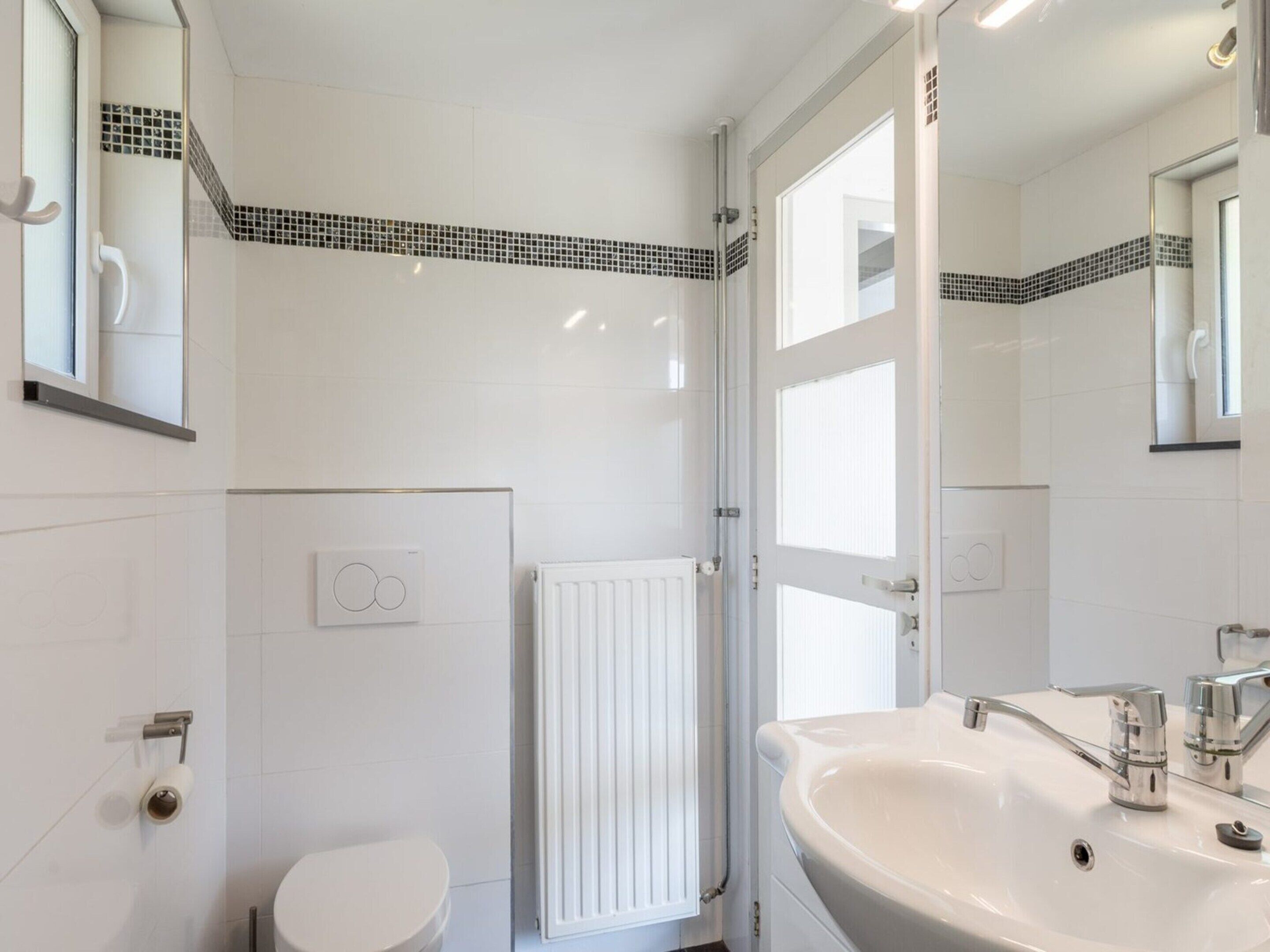 A modern bathroom with a white sink, a toilet, and a shower.