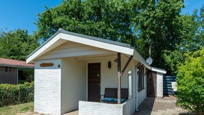 A small, single-story building with a covered porch and a door leading inside. - Holiday Home in Callantsoog Near Beach (Callantsoog)