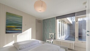 Ein Schlafzimmer mit zwei Betten, einem großen Fenster und einem Gemälde an der Wand.