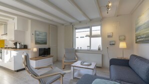 Ein modernes Wohnzimmer mit einer Couch, zwei Sesseln, einem Couchtisch und einem Fernseher.