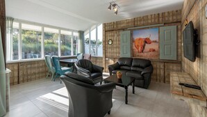 Een woonkamer met een groot raam, een bank, een bijzettafeltje en een schilderij van een stier.