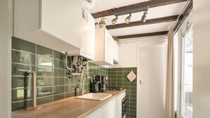 A kitchen with a wooden countertop, green backsplash, and a window with curtains. - Duinland 197 Bungalow in Sint Maartenszee (Sint Maartensvlotbrug)