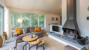 A modern living room with a fireplace, a sofa, a coffee table, and a TV. - Family Home by the Dunes (Sint Maartensvlotbrug)