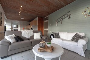 Uma sala de estar moderna com dois sofás, uma mesa de centro e teto de madeira.