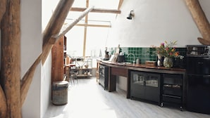Una cocina con vigas de madera, salpicadero de azulejos verdes y un refrigerador negro.