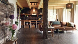 Un interior rústico con suelo de madera, un sofá de cuero marrón y una pared de ladrillo.