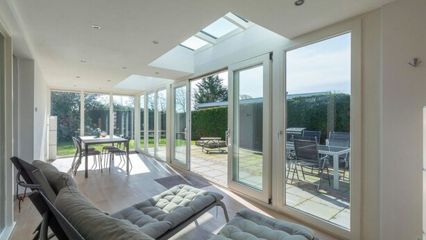 A spacious room with a large sliding glass door leading to an outdoor patio area. - Bungalow With Sauna and Pool in Quiet Location (Sint Maartensvlotbrug)