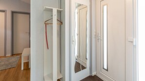 A modern interior with a white door, a mirror, and a coat rack. - Garnekuul 49 Holiday Home in Callanstoog (Callantsoog)