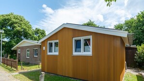 A small, single-story wooden house with a white window and a number '49' sign. - Garnekuul 49 Holiday Home in Callanstoog (Callantsoog)