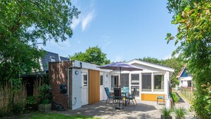 A single-story house with a patio area, a covered outdoor seating area, and a visible solar panel array on the roof. - Garnekuul 49 Holiday Home in Callanstoog (Callantsoog)