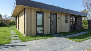 A modern two-story house with a flat roof, large windows, and a wooden exterior. - Spacious Bunglow With Garden (Sint Maartensvlotbrug)