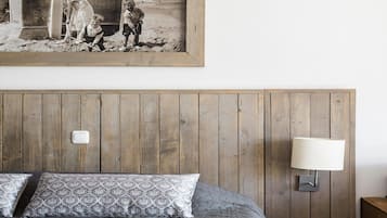 A bedroom with a wooden headboard, a bed with patterned pillows, a nightstand, and a wall-mounted lamp.