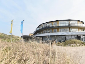 A modern building with a curved roof, multiple balconies, and a flat entrance area. - Seaside Double Duyn Suites (Callantsoog)