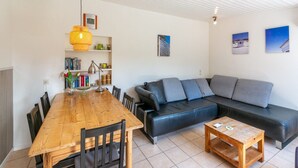 Un salon moderne avec une table à manger en bois, un canapé en cuir noir et une table basse en bois.