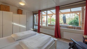 Une chambre avec deux lits, une armoire, une fenêtre avec des rideaux et une vue sur l’extérieur.