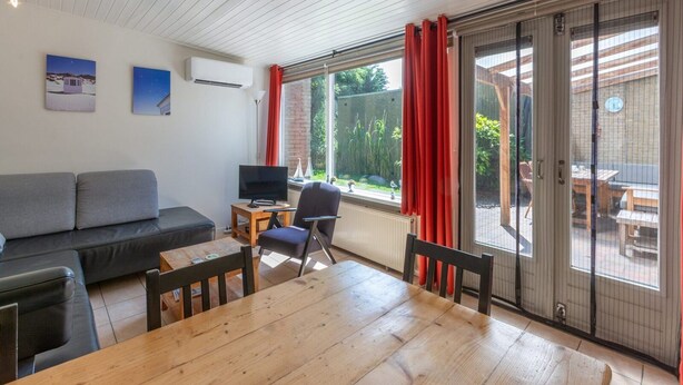 Un salon comprenant un canapé, un téléviseur, une table en bois et un coin repas.