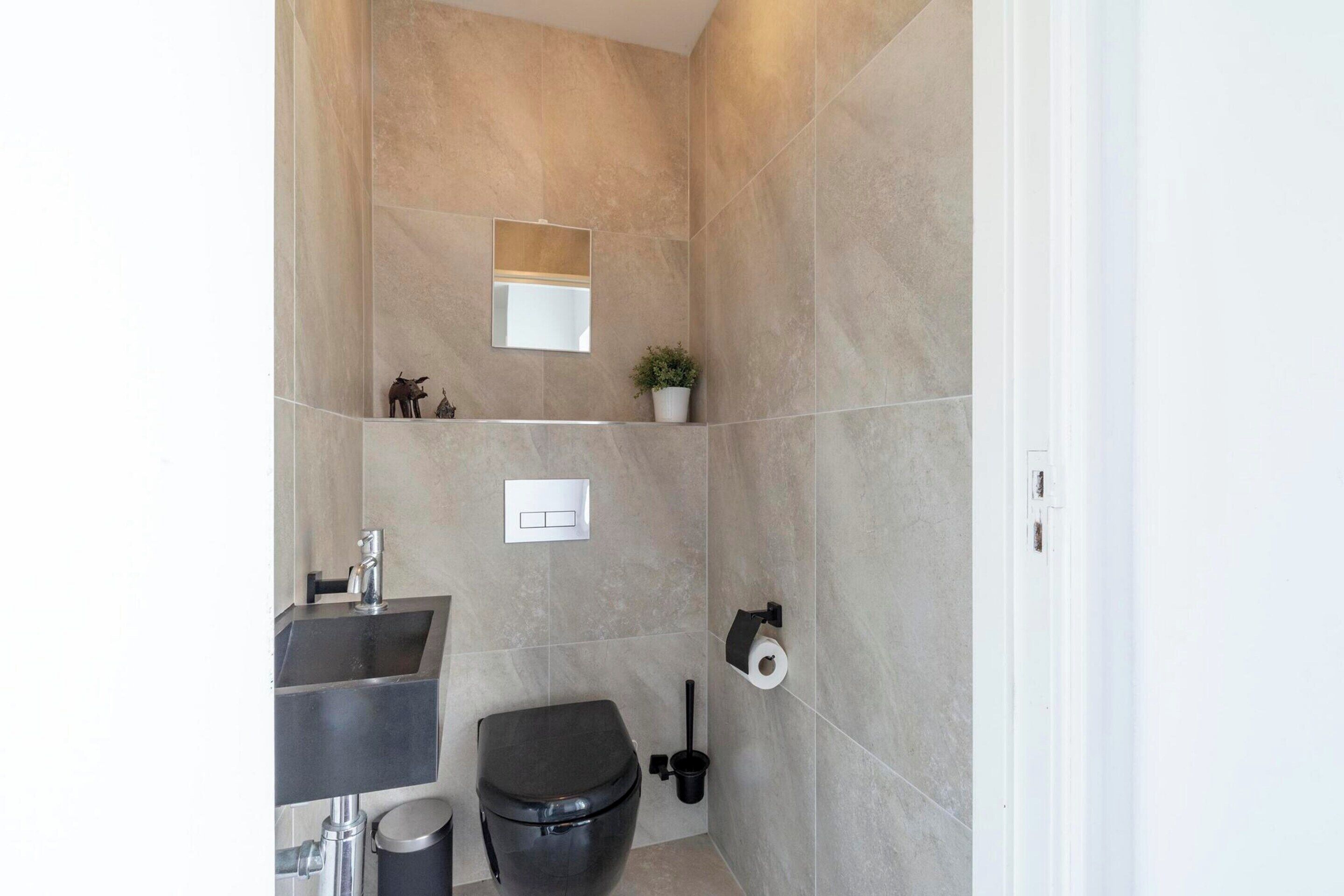 Et moderne badeværelse med vask, toilet og spejl.