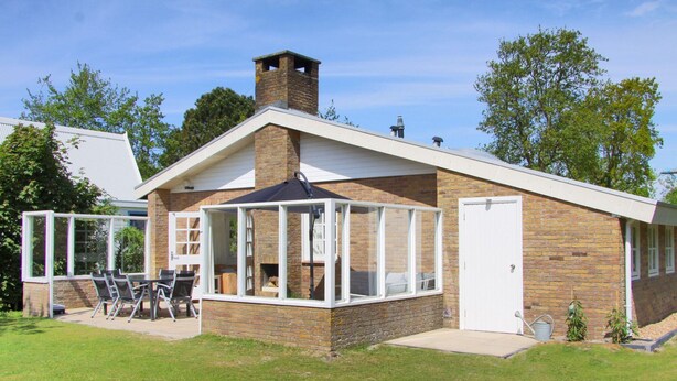 A modern house with a brick exterior, a large glass windowed porch, and a chimney.