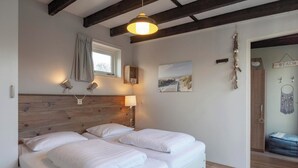 Una camera da letto con due letti, una testiera in legno, una finestra con tenda, lampade a parete e decorazioni a tema spiaggia.