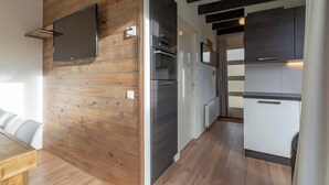 Una cucina moderna con rivestimenti in legno, forno a incasso e televisore a schermo piatto montato a parete.