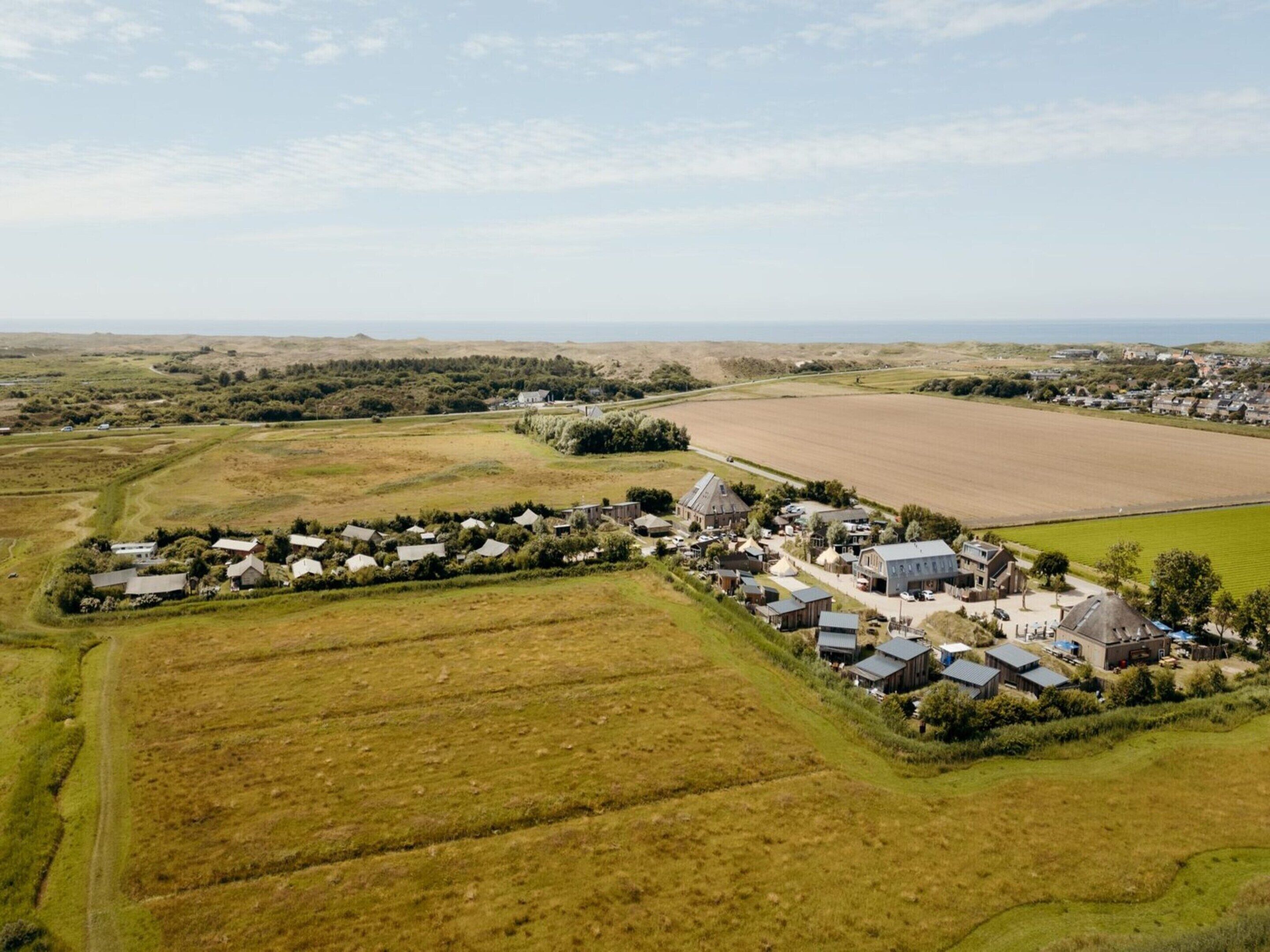 An aerial view of a rural village with houses, fields, and a large open area.