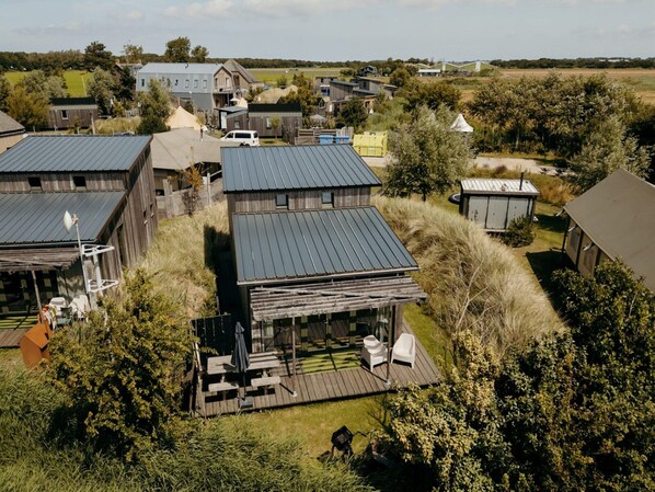 A modern house with a large deck, surrounded by a rural landscape. - Rustic Beach Getaway w/ Bikes (Callantsoog)
