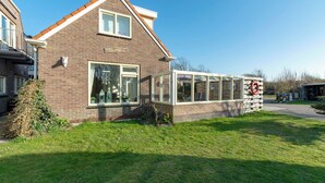 Et toetagers hus med facade af mursten, store vinduer og en tilbygning i glas.