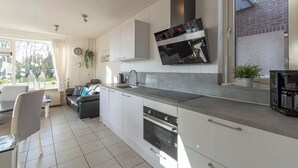 Et moderne køkken med hvide skabe, indbygget ovn og et stort vindue.