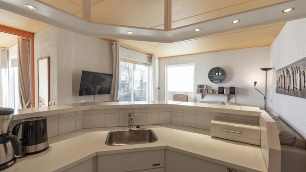 A modern kitchen with a built-in sink, a coffee maker, and a television on the wall. - Cozy Holiday Home With Terrace (Callantsoog)