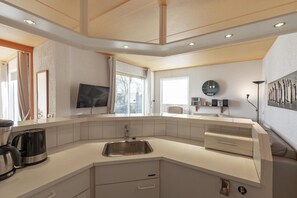 Enjoy cooking in this well-lit kitchen with a curved countertop, dishwasher, and flat-screen TV.