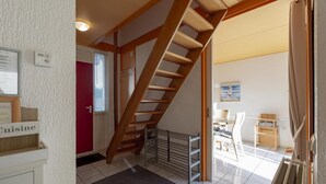 A staircase leading to a second floor, a dining area with a 'Cuisine' sign, and a view of the outside through a window. - Cozy Holiday Home With Terrace (Callantsoog)