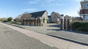 A residential street with houses, a paved sidewalk, and a street lamp. - Cozy Holiday Home With Terrace (Callantsoog)