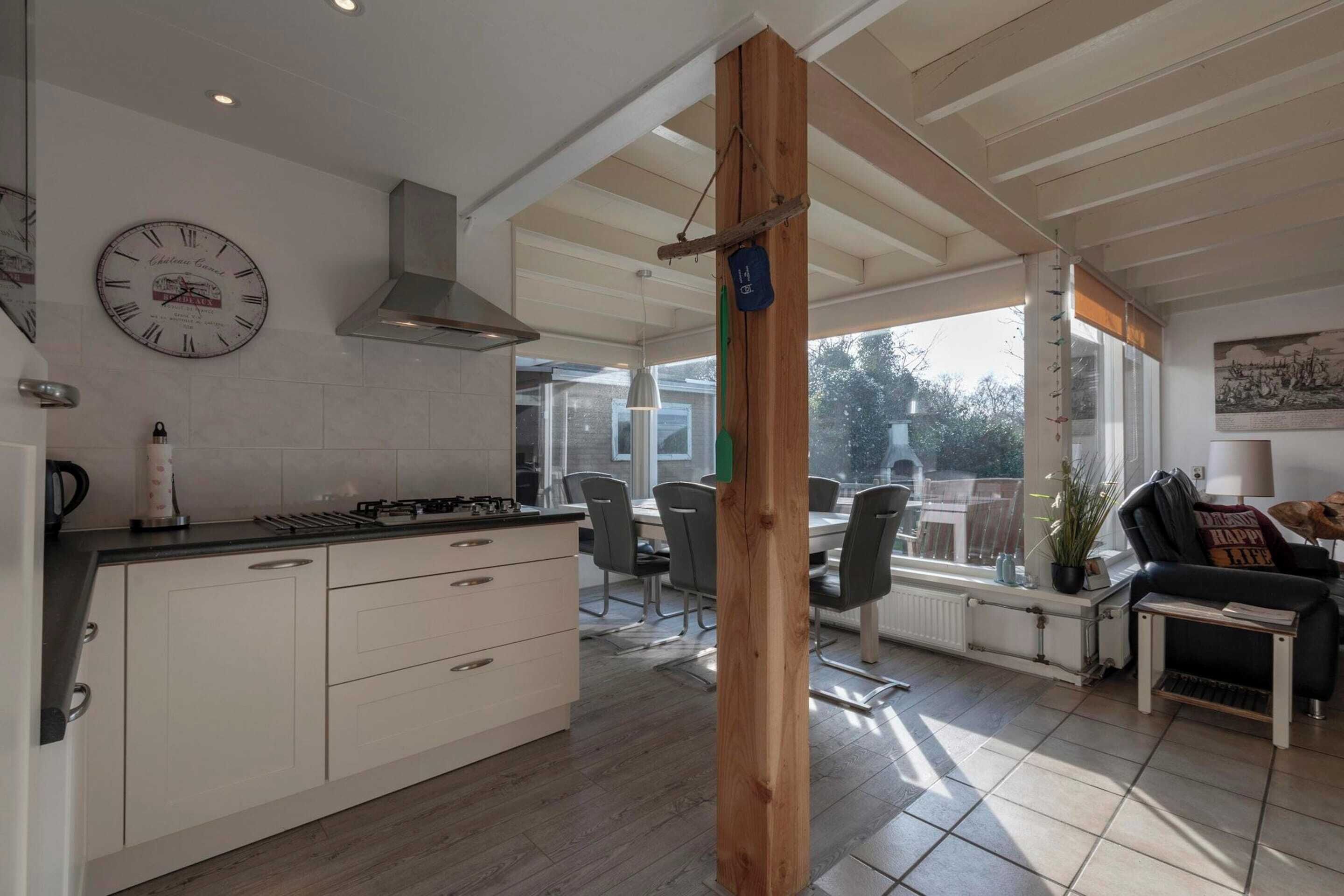 A modern kitchen with white cabinets, a black countertop, and a clock on the wall.