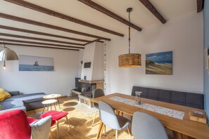 Un salon chaleureux avec une table à manger en bois, des sièges confortables, une cheminée et des œuvres d’art accrochées aux murs.