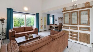 Ein geräumiges Wohnzimmer mit einem braunen Ledersofa, einem Holztisch und einer weißen Kommode mit Glastüren.