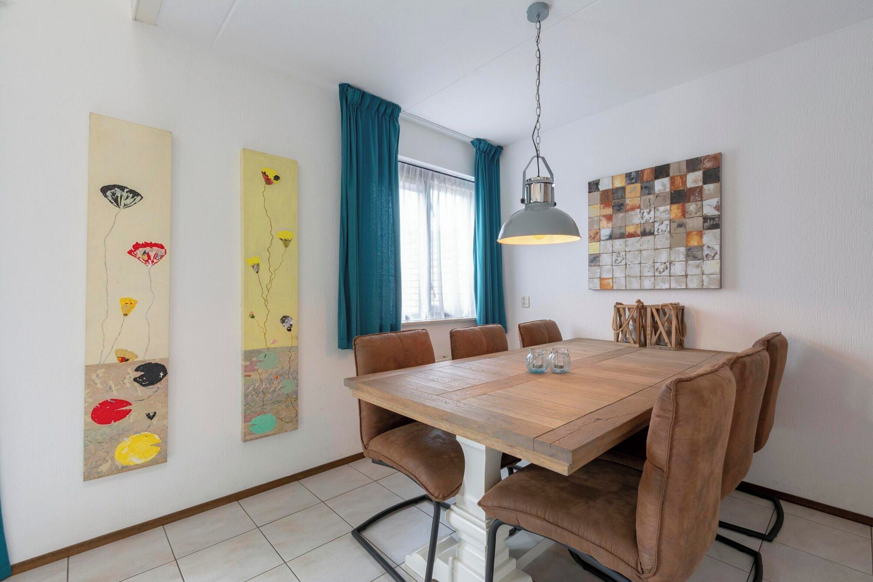 Un comedor con mesa de madera, sillas tapizadas en tono marrón y una lámpara colgante.